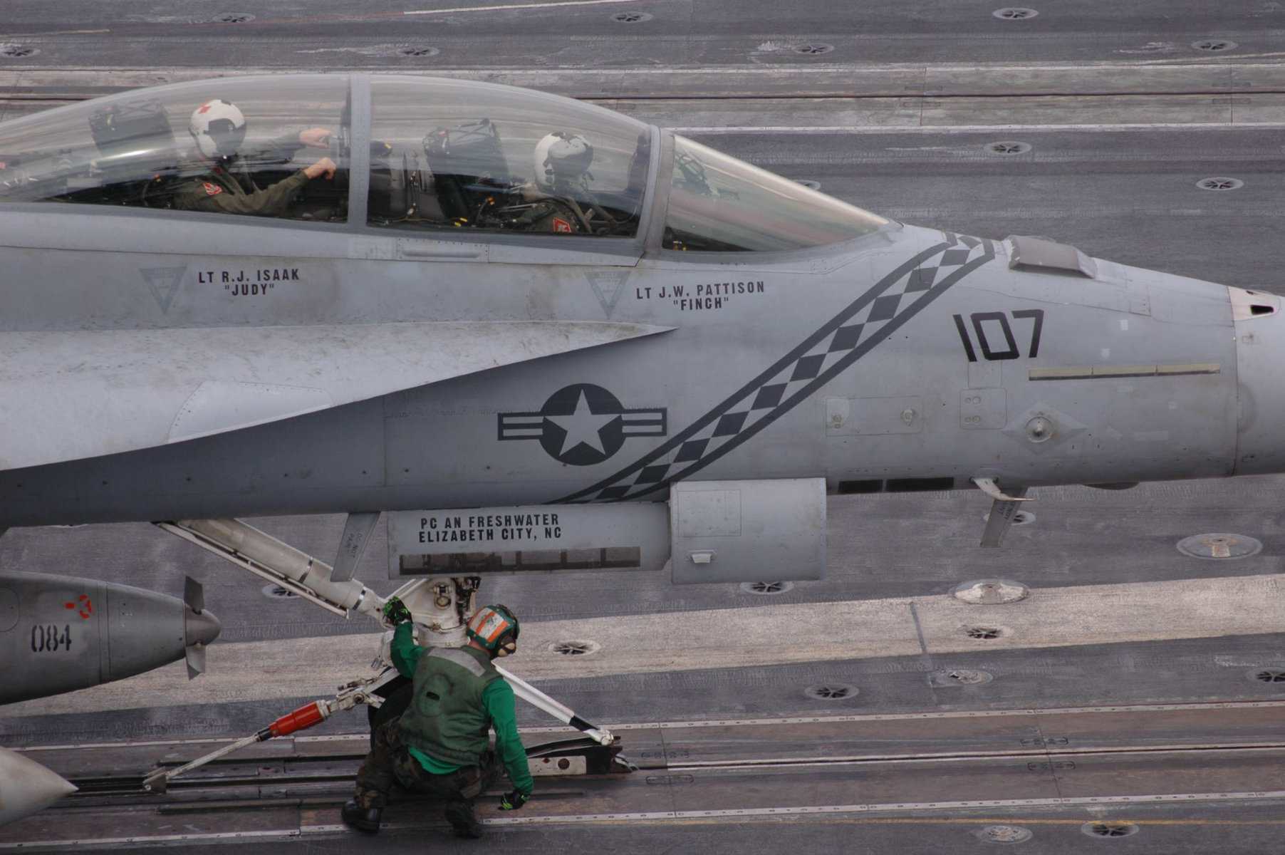 A sailor attaches the landing gear of an F/A-18 Super Hornet to the deck catapult on the aircraft carrier USS Kitty Hawk, 2025. Photo credits: U.S. Navy