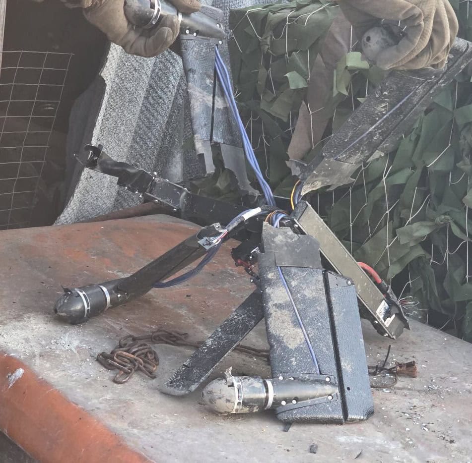 Russian invaders hold the remains of a German HX-2 drone. February 2026. Ukraine. Source: t.me/UAVDEV