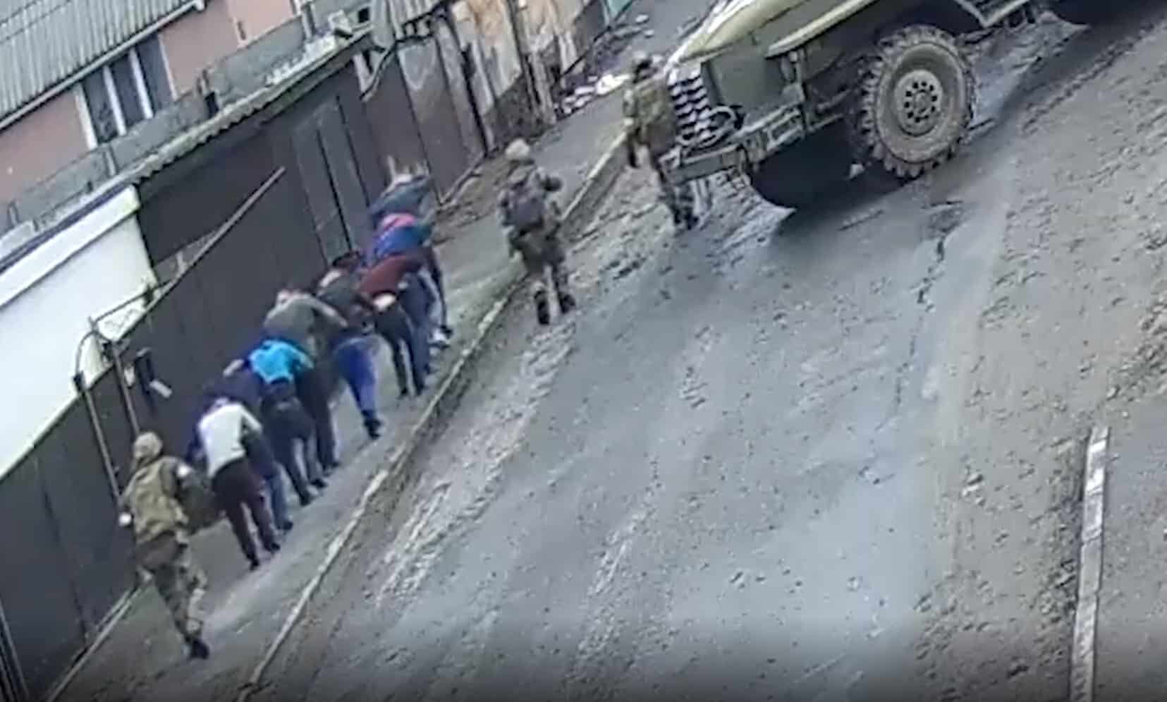 Russian soldiers in Bucha lead Ukrainian prisoners, some of whom will be killed. March 2022. Ukraine. Screenshot from NYT video