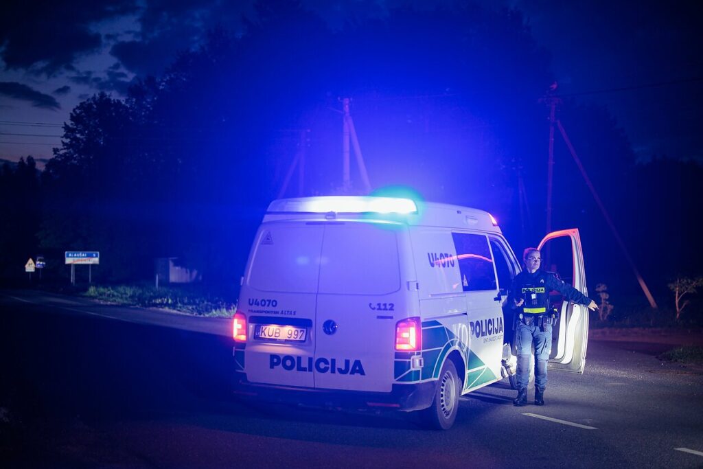 Поліцейський автомобіль із увімкненими проблисковими маячками чергує на дорозі в Утенському районі Литви, де зафіксували падіння безпілотника. Фото D. Umbrasas / LRT
