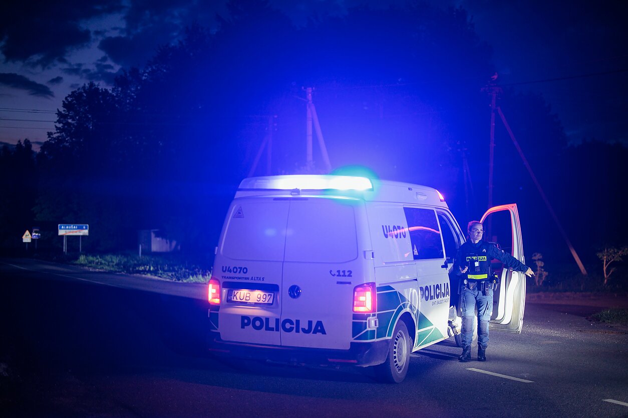 Поліцейський автомобіль із увімкненими проблисковими маячками чергує на дорозі в Утенському районі Литви, де зафіксували падіння безпілотника. Фото D. Umbrasas / LRT