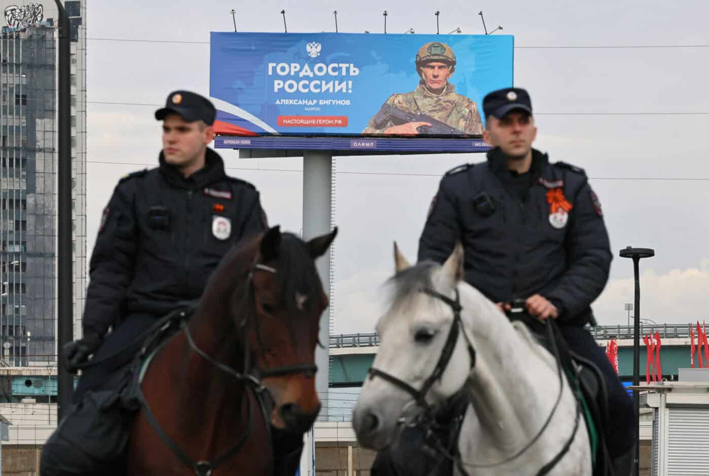 Поліцейські патрулюють вулицю біля рекламного банера в Москві. Фото: Анастасія Барашкова/Reuters.